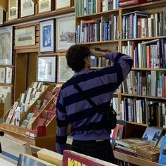 a person standing in front of a bookshelf looking through the window at some books