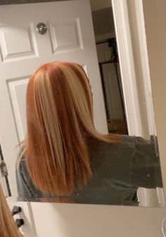 a woman with long red hair looking at herself in the mirror