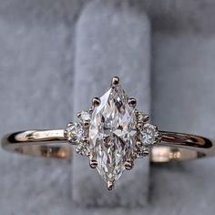 an engagement ring with a pear shaped diamond in the center and three smaller diamonds on each side