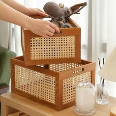 a person holding a stuffed animal in a wooden box on top of a coffee table