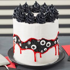 a white cake with black icing and red sprinkles is on a plate