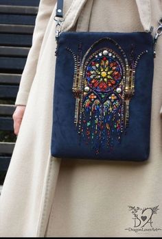 a woman is carrying a blue purse with beaded details on it and an elaborate design