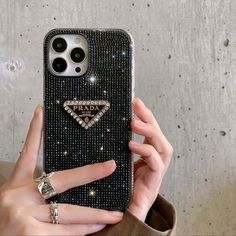 a woman holding up her phone case with diamonds on it