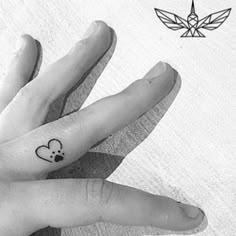 two fingers with small tattoos on them, one has a mouse and the other has a heart