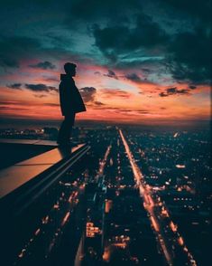 a person standing on top of a tall building looking at the city lights in the distance