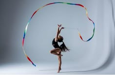 a woman is holding a colorful streamer in the air while standing on one leg