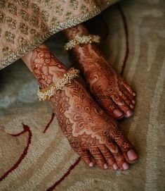 the feet and hands of a bride with henna tattoos on their feet are adorned with gold jewelry