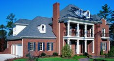 a large red brick house with white trim and blue shutters on the front door