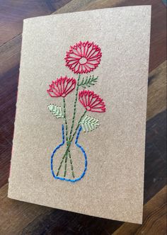 an embroidered card with flowers in a vase