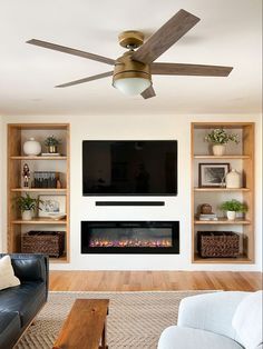 a living room with a ceiling fan, fireplace and entertainment center in the middle of it