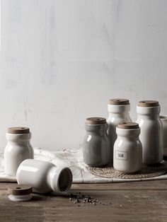 several white jars sitting on top of a wooden table