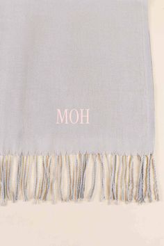 a gray and white blanket with the word moh on it's fringes