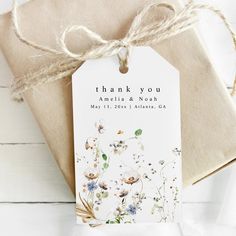 a thank you tag attached to a gift bag on a white wooden surface with twine