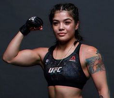 a woman with tattoos on her arm holding a boxing glove and looking at the camera