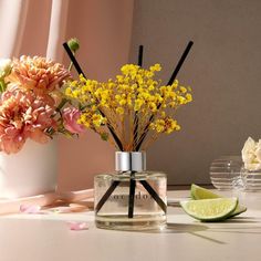 a vase filled with yellow flowers next to a lime slice