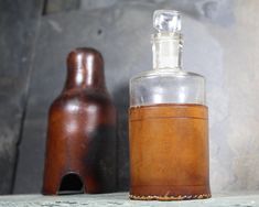 an empty glass bottle sitting on top of a table next to a brown vase and wooden object