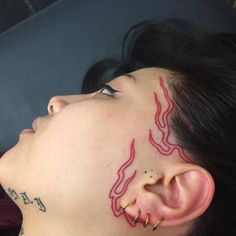 a woman with tattoos on her face and ear piercings is looking up at the sky