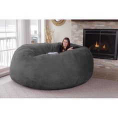 a woman sitting in a large bean bag chair next to a fire place and fireplace