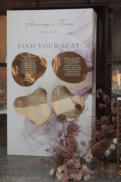 a table with flowers on it and a sign in the background that says find your seat