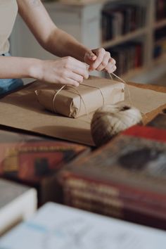 a woman is wrapping up a brown paper bag with twine and yarn on it