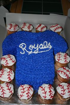 a cake in the shape of a baseball jersey with some cupcakes around it