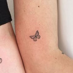 two small tattoos on the arms of women with butterflies flying around each arm and behind them