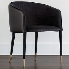 a black chair sitting on top of a hard wood floor next to a white wall