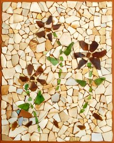 a mosaic tile with leaves on it in brown, white and green colors is shown