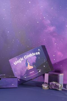 the magic goddess box is sitting on top of some rocks in front of a purple background