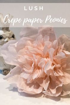 a pink flower sitting on top of a table next to two small figurines