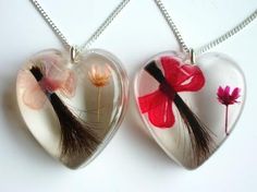 two heart shaped pendants with flowers and feathers