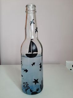 a glass bottle with an image of a boat in the water and birds painted on it