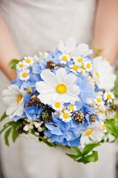 a bride holding a bouquet of blue and white flowers