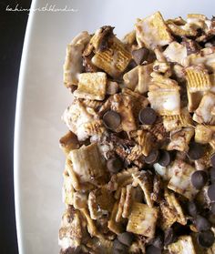 a white plate topped with chocolate chips and cereal granola mix next to a cup of coffee