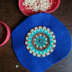 two bowls with beaded designs sit on a table next to one bowl and another container