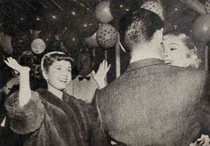 an old black and white photo of two women dancing at a party with balloons in the background