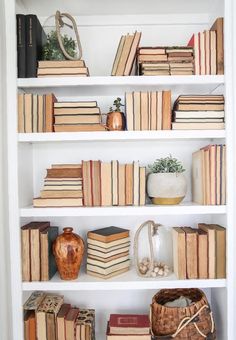 a white book shelf filled with lots of books and wicker baskets on top of it