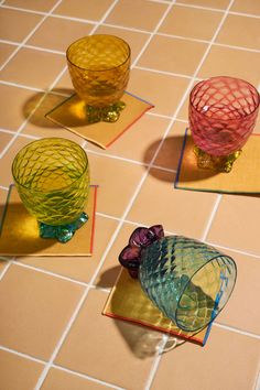 three colorful glass vases sitting on top of a tiled floor