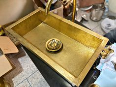 a gold sink sitting on top of a counter next to a pile of boxes and other items