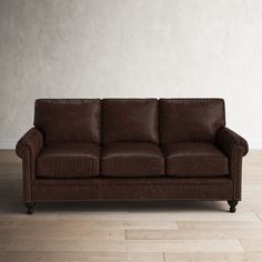 a brown leather couch sitting on top of a hard wood floor