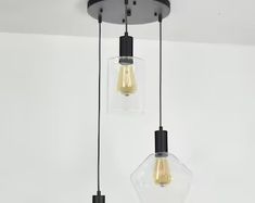 three light fixtures hanging from a ceiling in a room with white walls and flooring