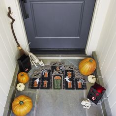 a front door decorated for halloween with pumpkins and other decorations on the ground next to it