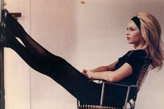 a woman is sitting in a chair with her legs crossed and wearing black tights