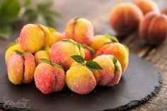 several pieces of fruit sitting on top of a wooden table next to green leaves and peaches