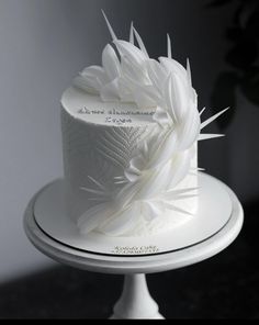 a white wedding cake with feathers on top