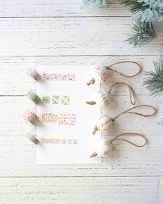 a paper with some decorations on top of it next to pine cones and twine