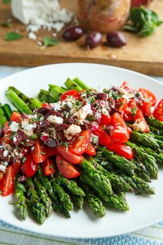 a white plate topped with asparagus, tomatoes and feta cheese on top of it