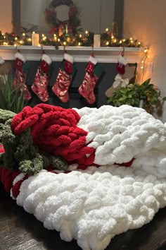 a pile of blankets sitting on top of a wooden table next to a fire place