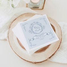 two napkins sitting on top of a wooden plate next to a vase with flowers