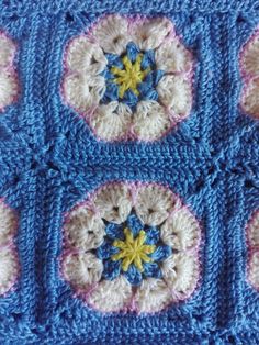 a crocheted blue and white square with yellow flowers on the center is shown